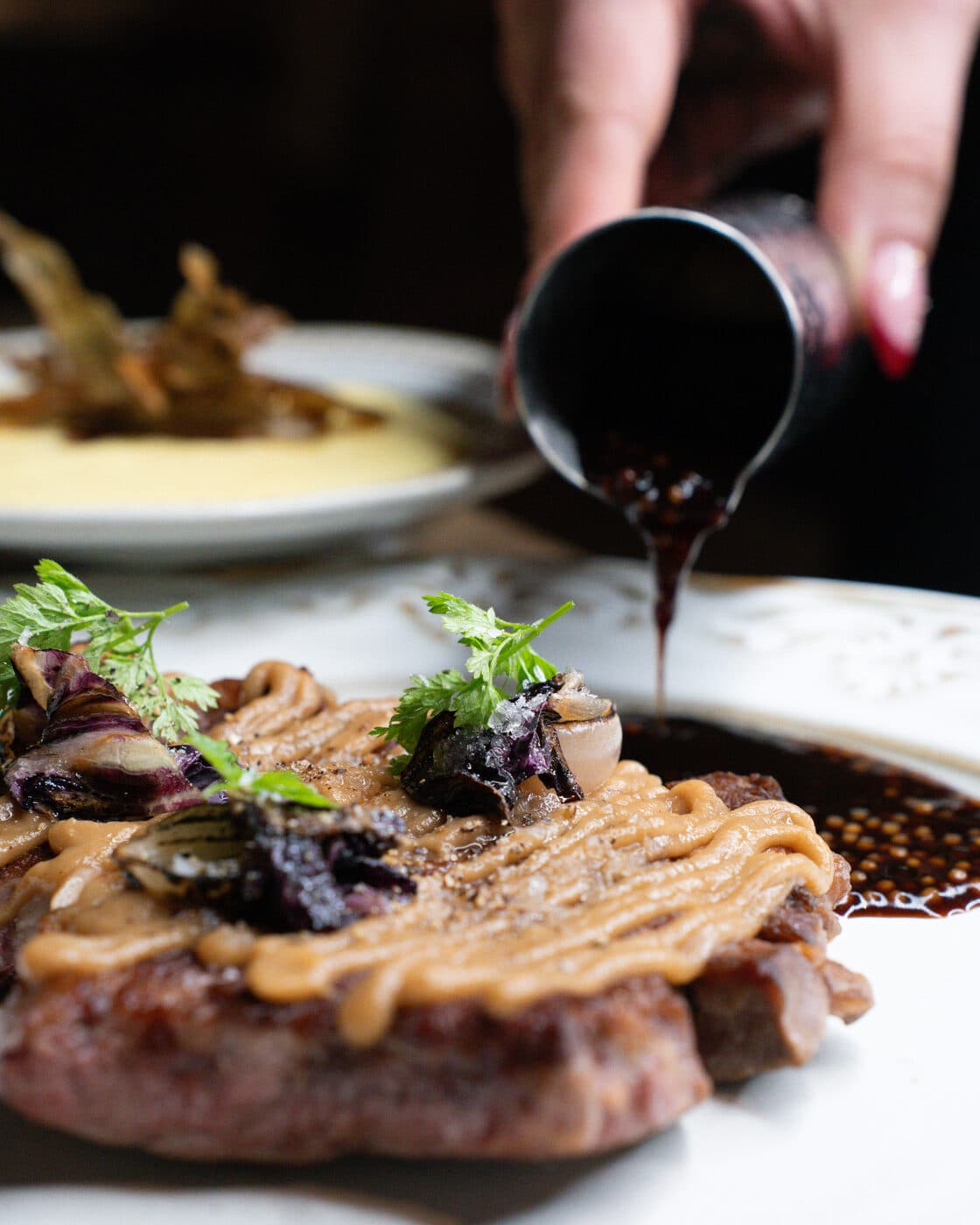Angerichtetes Gericht, am Tisch mit Sauce vollendet