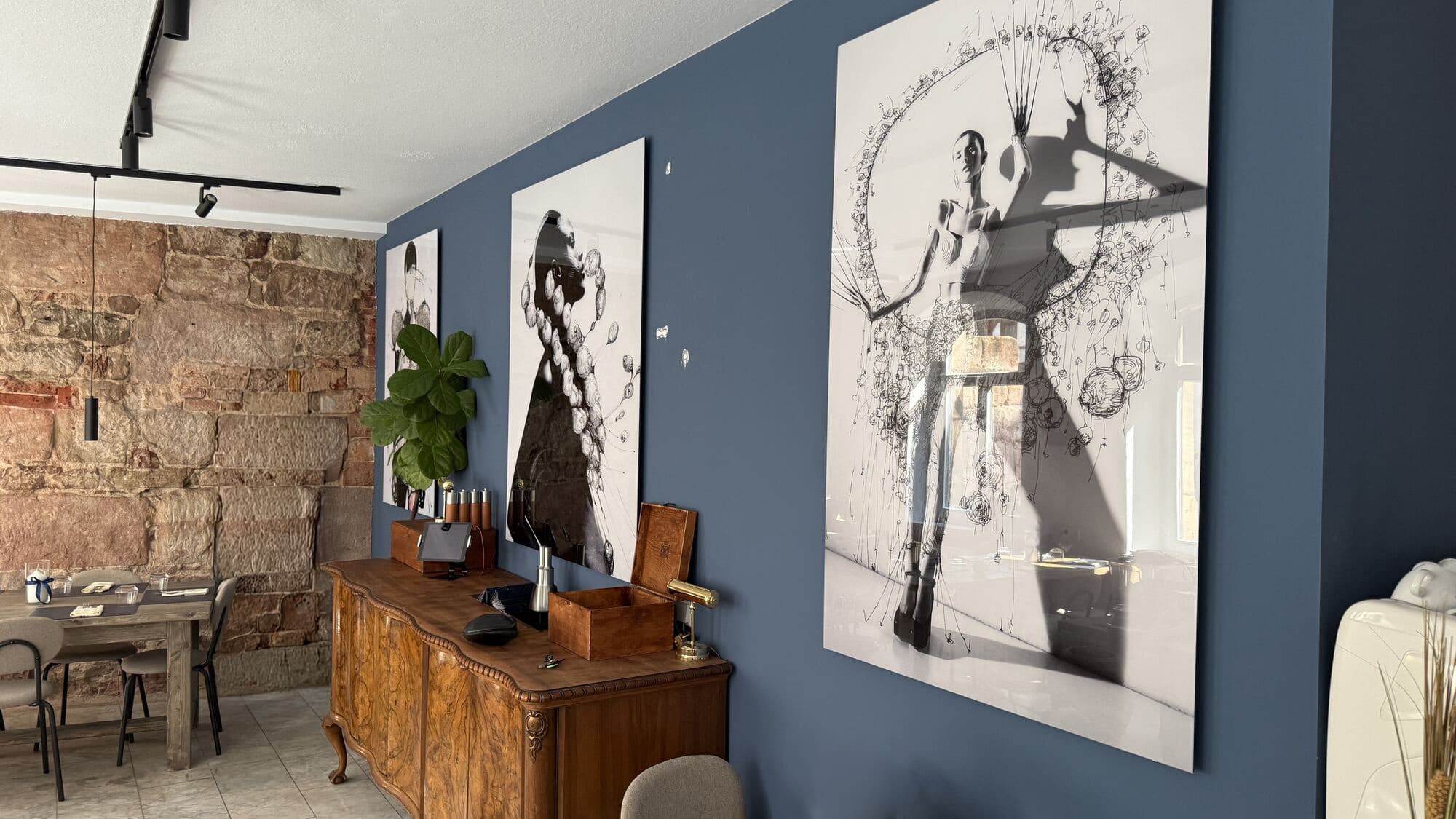 Gastraum mit blauer Wand, Kunstdrucken und antiker Kommode